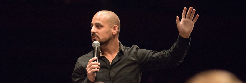 Eric Mina on stage with his arm raised